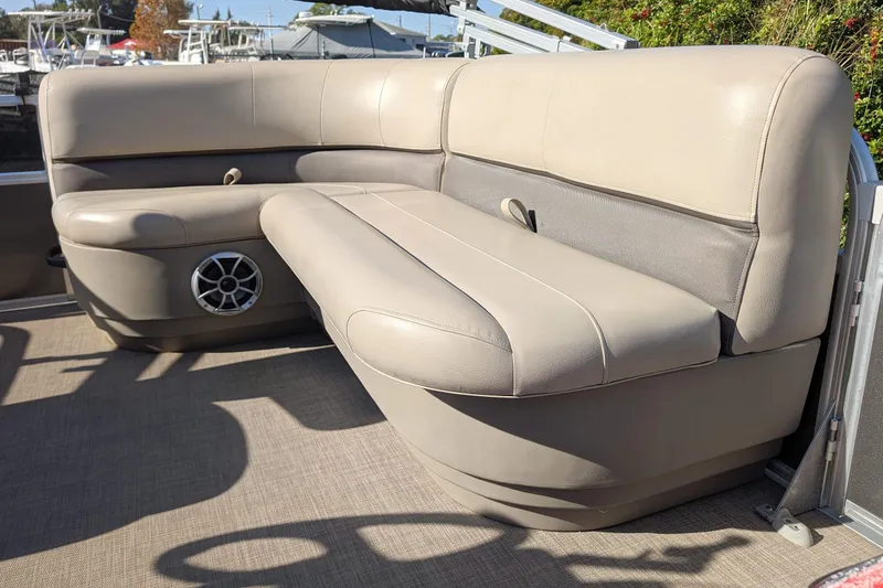 Slide: The Image of 2025 Sun Tracker Party Barge 16 DLX interior seating with speaker, beige upholstery. - 12