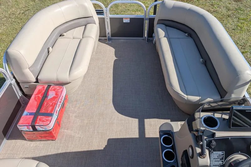 Slide: The Image of 2025 Sun Tracker Party Barge 16 DLX interior with beige seating and red life jacket box. - 8
