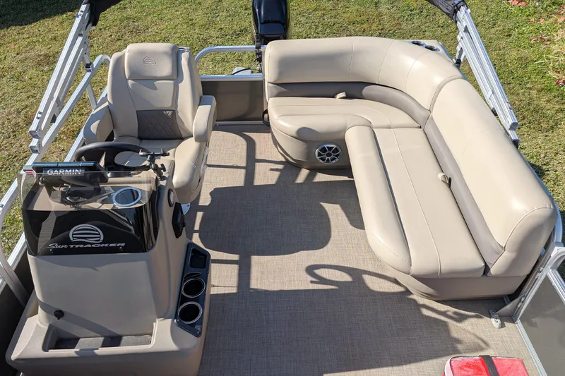 Slide: The Image of 2025 Sun Tracker Party Barge 16 DLX interior with beige seating and steering console. - 9