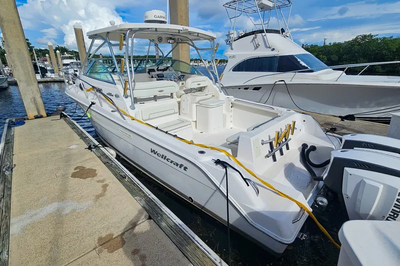 Slide: The Image of 2005 Wellcraft 290 Coastal boat docked at marina, featuring spacious deck and twin engines. - 20