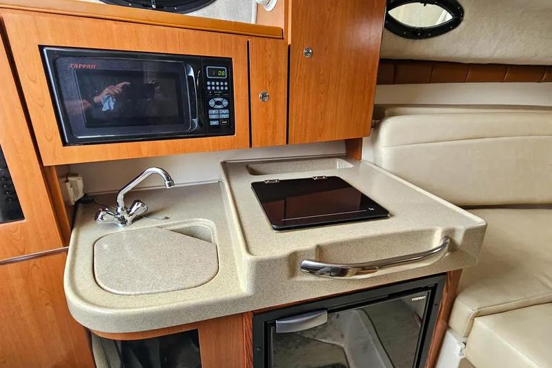 Slide: The Image of 2005 Wellcraft 290 Coastal interior kitchen with microwave, sink, and stove. - 30