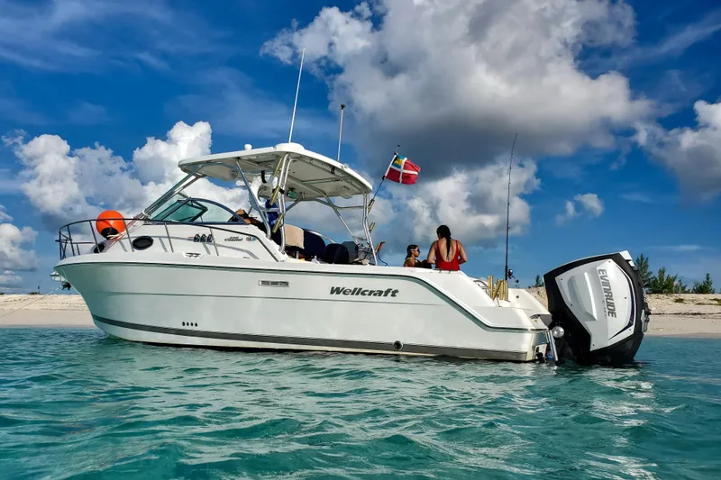 Slide: The Image of 2005 Wellcraft 290 Coastal boat anchored near a sandy beach under a blue sky. - 6