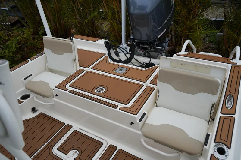 Slide: The Image of 2017 Skeeter SX230 boat interior with cushioned seats and motor, surrounded by greenery. - 42