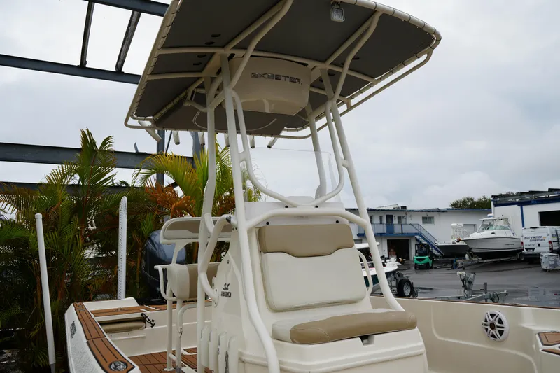 Slide: The Image of 2017 Skeeter SX230 boat with T-top, docked near palm trees and other boats. - 8