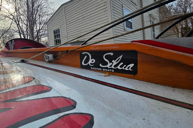 Slide: The Image of 1987 De Silva F Class Race boat with wooden detailing and logo, parked near a house. - 19