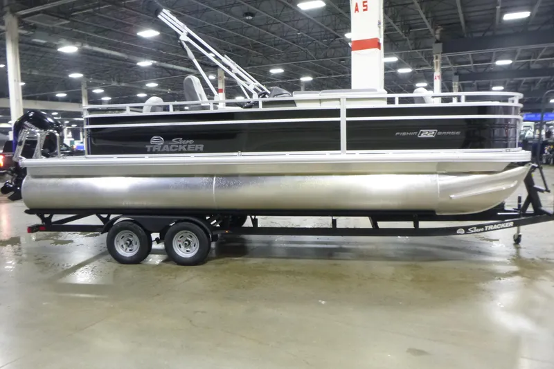 The Image of 2026 Sun Tracker Fishin' Barge 22 DLX pontoon boat displayed indoors on a trailer. - 1