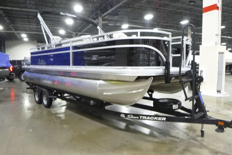 Slide: The Image of 2026 Sun Tracker Fishin' Barge 22 DLX pontoon boat on trailer in indoor showroom. - 3