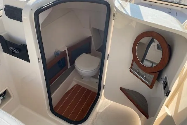 Slide: The Image of 2022 Grady-White Freedom 235 boat interior with compact bathroom and wooden accents. - 17