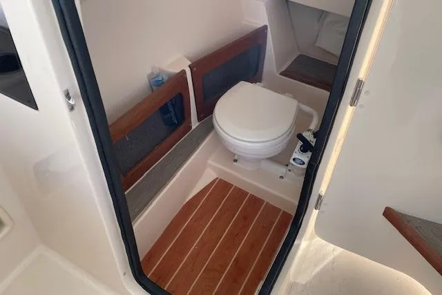 Slide: The Image of 2022 Grady-White Freedom 235 boat interior with compact marine toilet and wooden flooring. - 18
