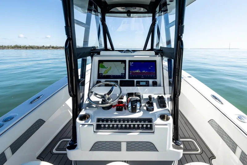 Slide: The Image of 2022 Invincible 33 Open Fisherman boat dashboard with navigation screens on calm water. - 11
