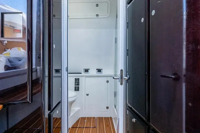 Slide: The Image of Interior of 2020 HCB 53 Sueños boat featuring a compact bathroom with wooden flooring. - 20