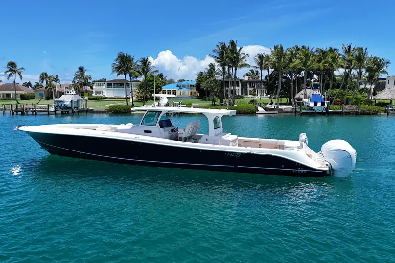 Slide: The Image of 2020 HCB 53 Sueños boat on clear blue water, surrounded by palm trees and luxury homes. - 2