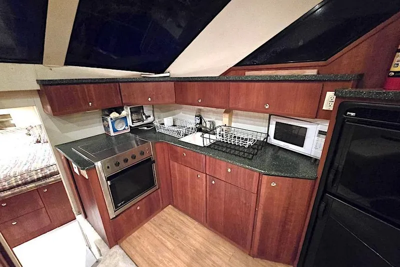 Slide: The Image of 2000 Silverton 392 Motor Yacht kitchen with wood cabinets, stove, microwave, and sink. - 4