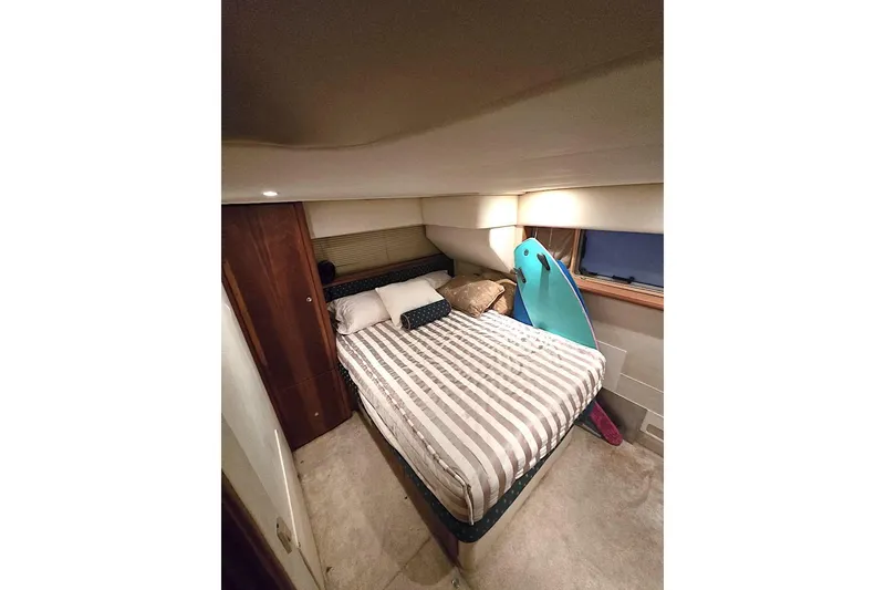 Slide: The Image of Cozy bedroom in 2000 Silverton 392 Motor Yacht with striped bedding and surfboard. - 7