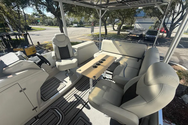 Slide: The Image of 2023 Starcraft SLS 3 Q DH boat interior with plush seating and table, parked outdoors. - 24