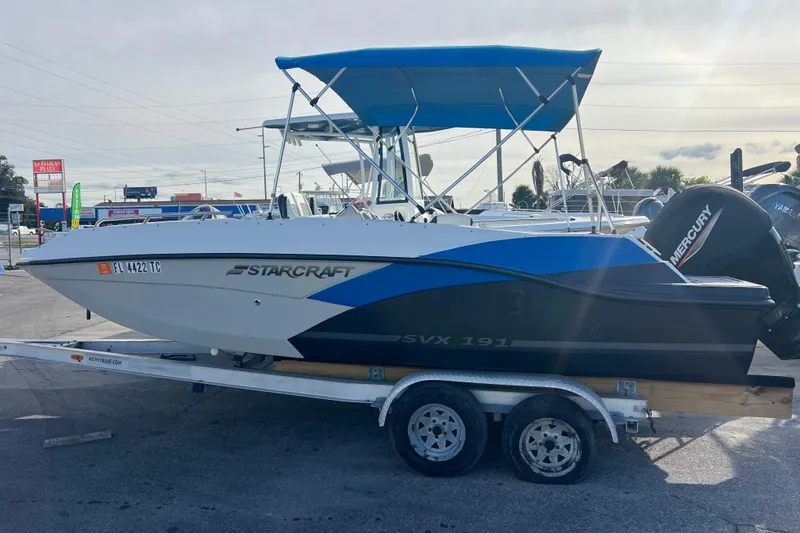 Slide: The Image of 2022 Starcraft SVX 191 OB boat on trailer with blue canopy and Mercury outboard motor. - 1