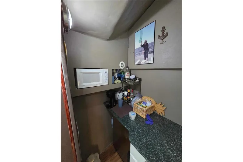 Slide: The Image of Compact kitchen area in a 2000 JM Custom 42 boat with microwave and countertop essentials. - 12
