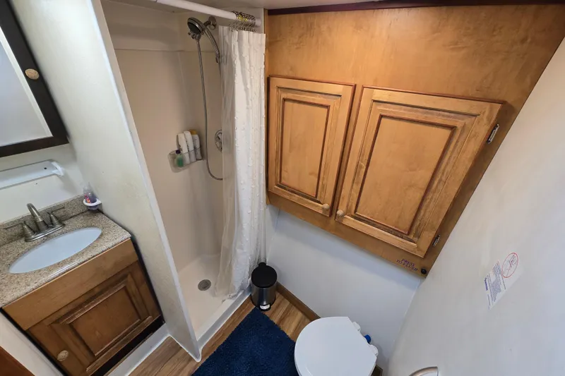 Slide: The Image of Bathroom interior of 2000 Custom 42 JM Sportfish, featuring shower, sink, and wooden cabinets. - 31