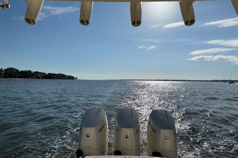 Slide: The Image of 2025 Scout 357 LXF boat with triple Mercury engines on a sunny day at sea. - 14