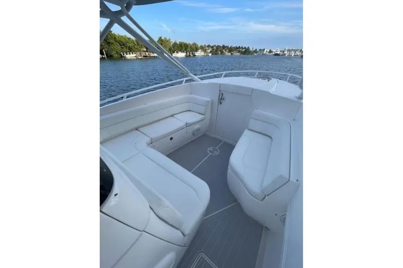 Slide: The Image of 2014 Intrepid 327 Cuddy boat interior with white seating, on calm water. - 16