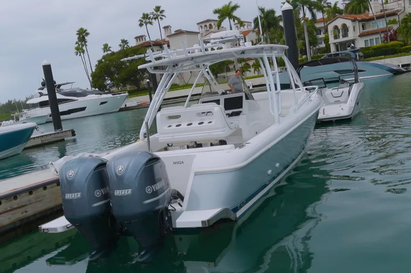 Slide: The Image of 2014 Intrepid 327 Cuddy boat docked with twin Yamaha engines in a marina. - 4