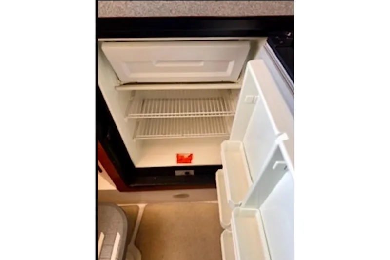 Slide: The Image of Open refrigerator inside 2002 Wellcraft 3300 Martinique boat, showing empty shelves and door compartments. - 13