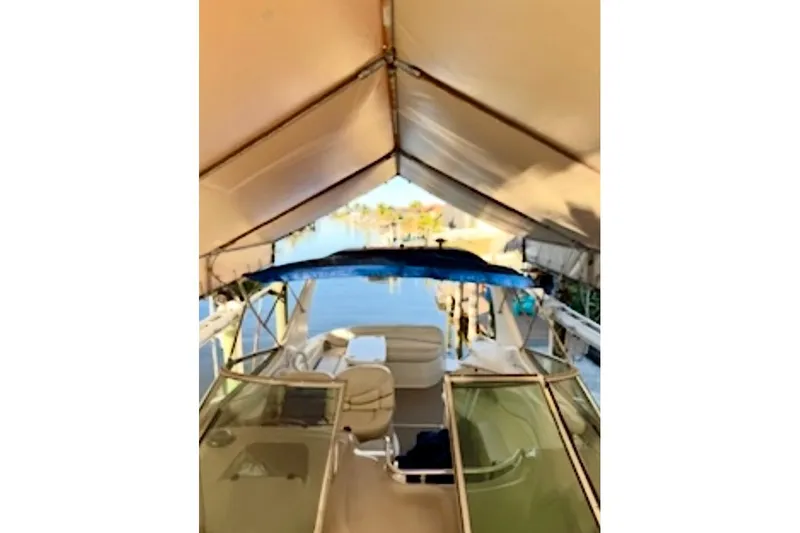 Slide: The Image of 2002 Wellcraft 3300 Martinique boat under canopy, docked by calm waters. - 3