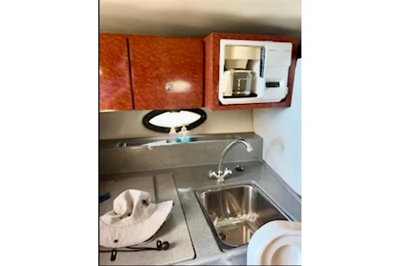 Slide: The Image of 2002 Wellcraft 3300 Martinique boat kitchen with sink, cabinets, and coffee maker. - 8