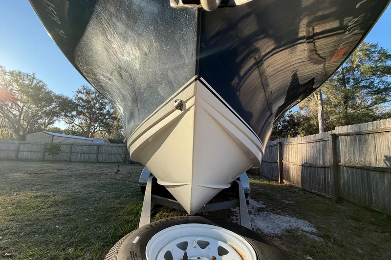 Slide: The Image of 2015 Sea Hunt Ultra 225 boat on trailer, viewed from below, in a sunny yard. - 12