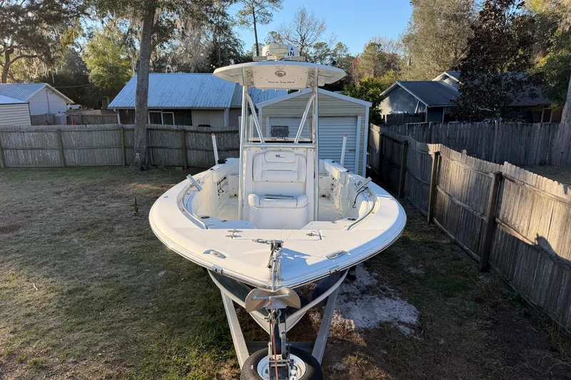 Slide: The Image of 2015 Sea Hunt Ultra 225 boat parked in a backyard, surrounded by fences and trees. - 13