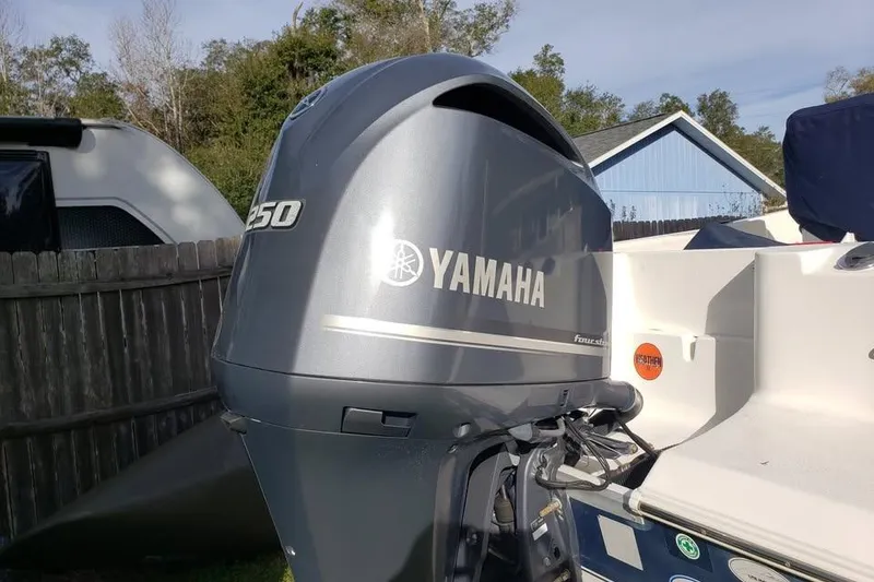 Slide: The Image of 2015 Sea Hunt Ultra 225 boat on trailer with Yamaha outboard motor in a yard. - 2