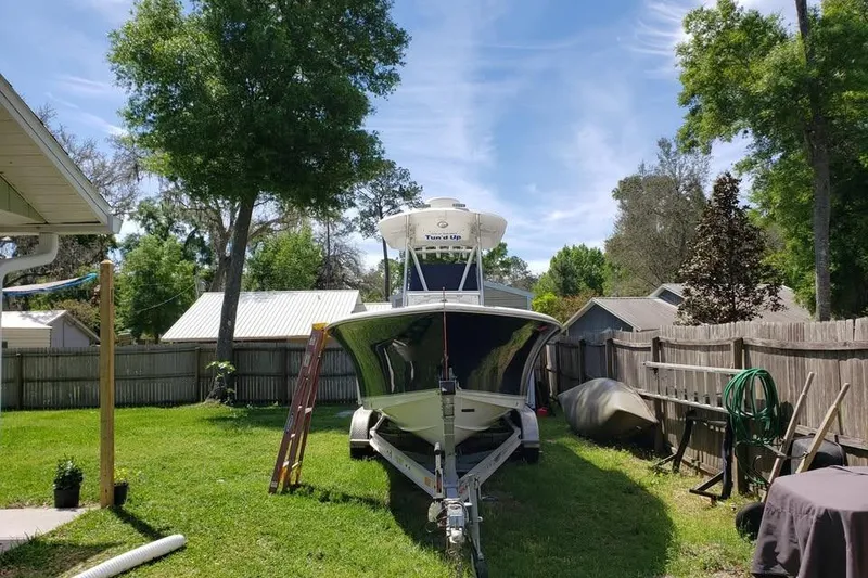 Slide: The Image of 2015 Sea Hunt Ultra 225 boat on trailer with Yamaha outboard motor in a yard. - 8