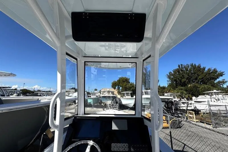 Slide: The Image of 2026 Blazer Bay 2400 boat interior with steering console, docked among other boats. - 21