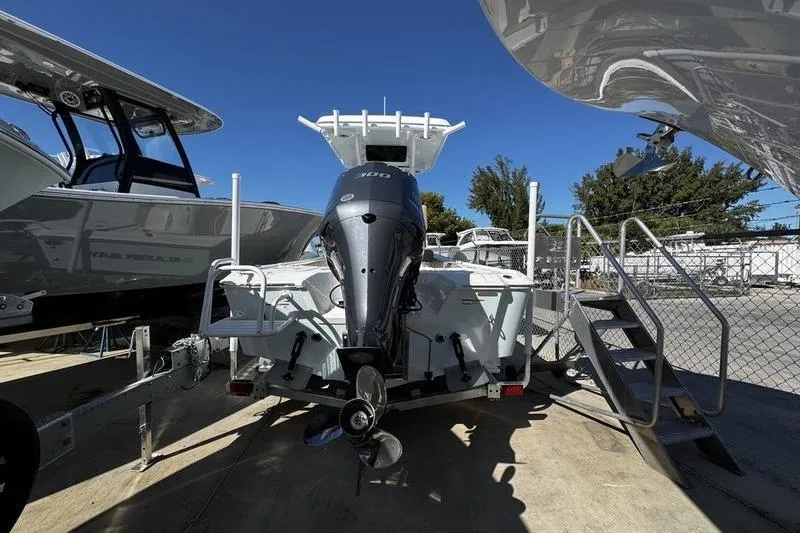 Slide: The Image of 2026 Blazer Bay 2400 boat with outboard motor, parked in a marina. - 3