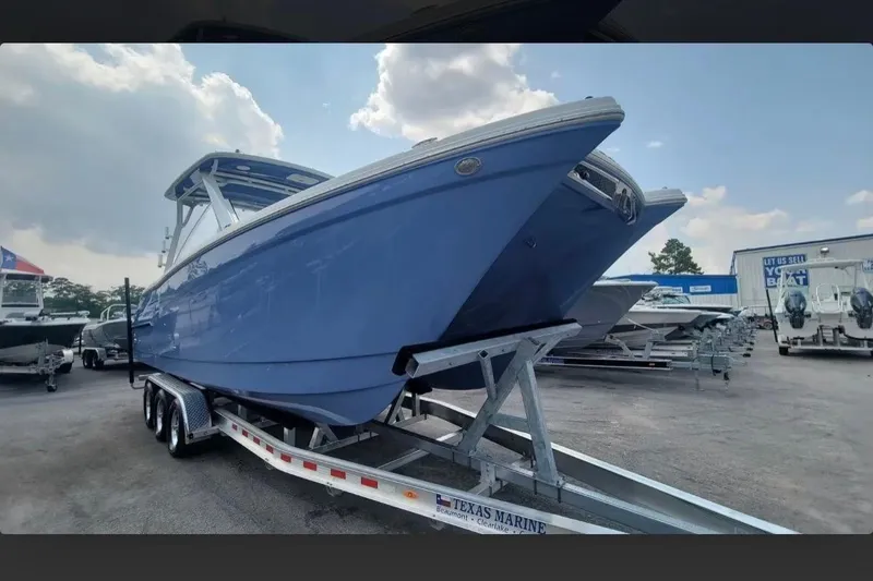 Slide: The Image of 2023 World Cat 280 DC-X boat on trailer at dealership under cloudy sky. - 2