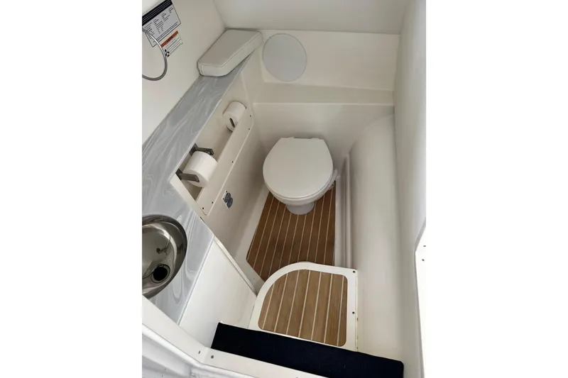 Slide: The Image of 2023 World Cat 280 DC-X boat bathroom with toilet, sink, and wooden flooring. - 26
