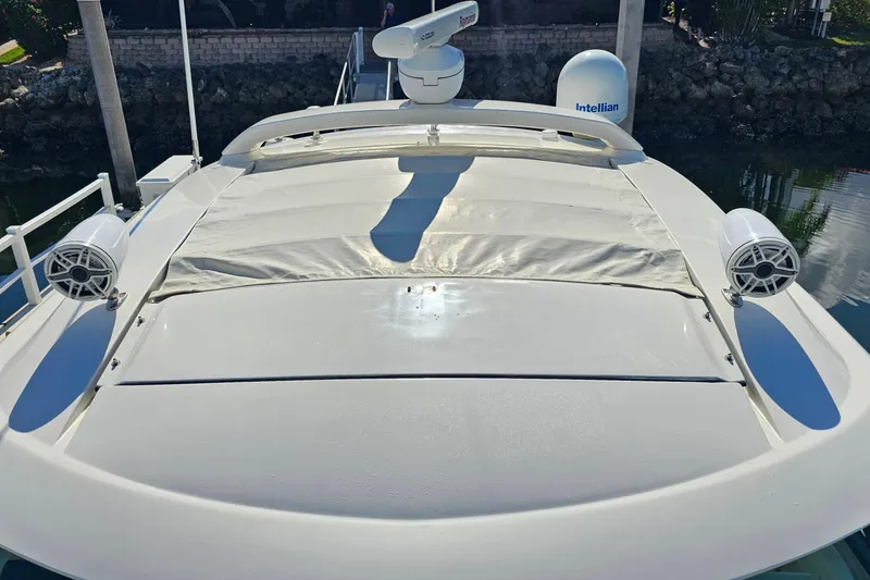 Slide: The Image of 2015 Sea Ray 410 Sundancer yacht with speakers and radar, docked by rocky shoreline. - 30