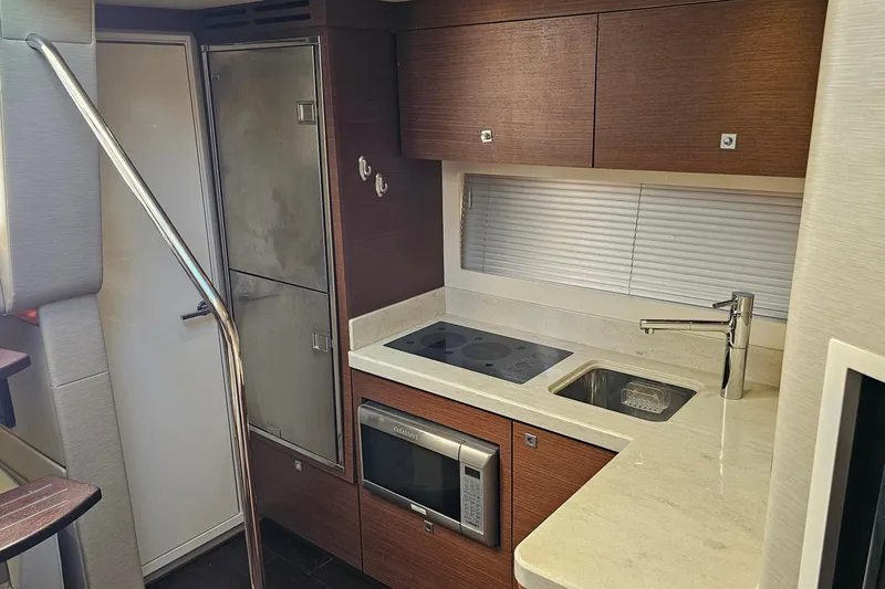 Slide: The Image of Modern kitchen in 2015 Sea Ray 410 Sundancer yacht with sleek appliances and wood cabinetry. - 42