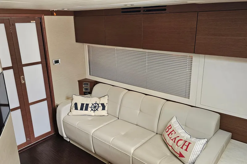 Slide: The Image of Interior of 2015 Sea Ray 410 Sundancer with beige sofa and nautical-themed pillows. - 46