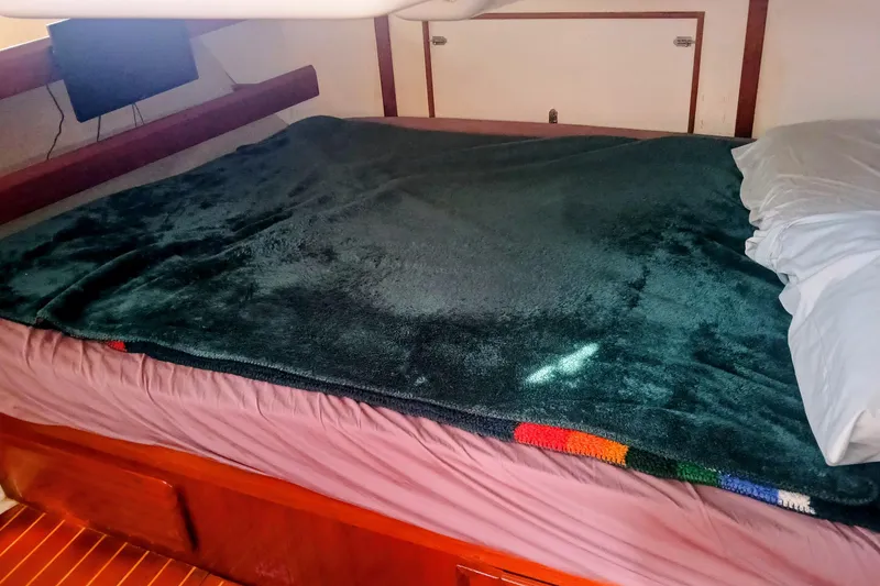 Slide: The Image of Cozy cabin bed in a 1994 Hunter Legend 40 sailboat, featuring a plush blanket and pillow. - 17