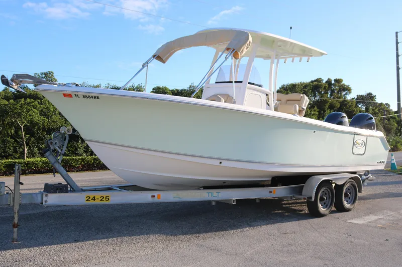 The Image of 2016 Sea Hunt Gamefish 25 boat on trailer, parked outdoors under clear sky. - 0