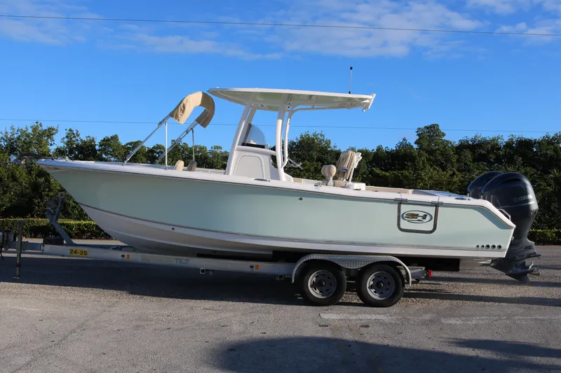 Slide: The Image of 2016 Sea Hunt Gamefish 25 boat on trailer, parked outdoors under blue sky. - 1