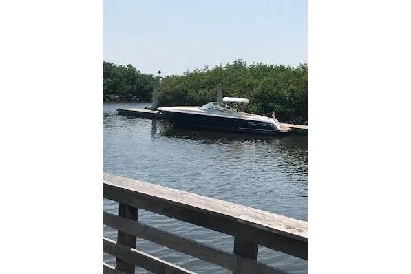 Slide: The Image of 2006 Chris Craft Corsair Heritage boat docked on calm water near lush greenery. - 3