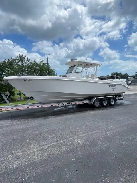The Image of 2014 Everglades 325 Center Console boat on a Blue Fin trailer, parked outdoors. - 0