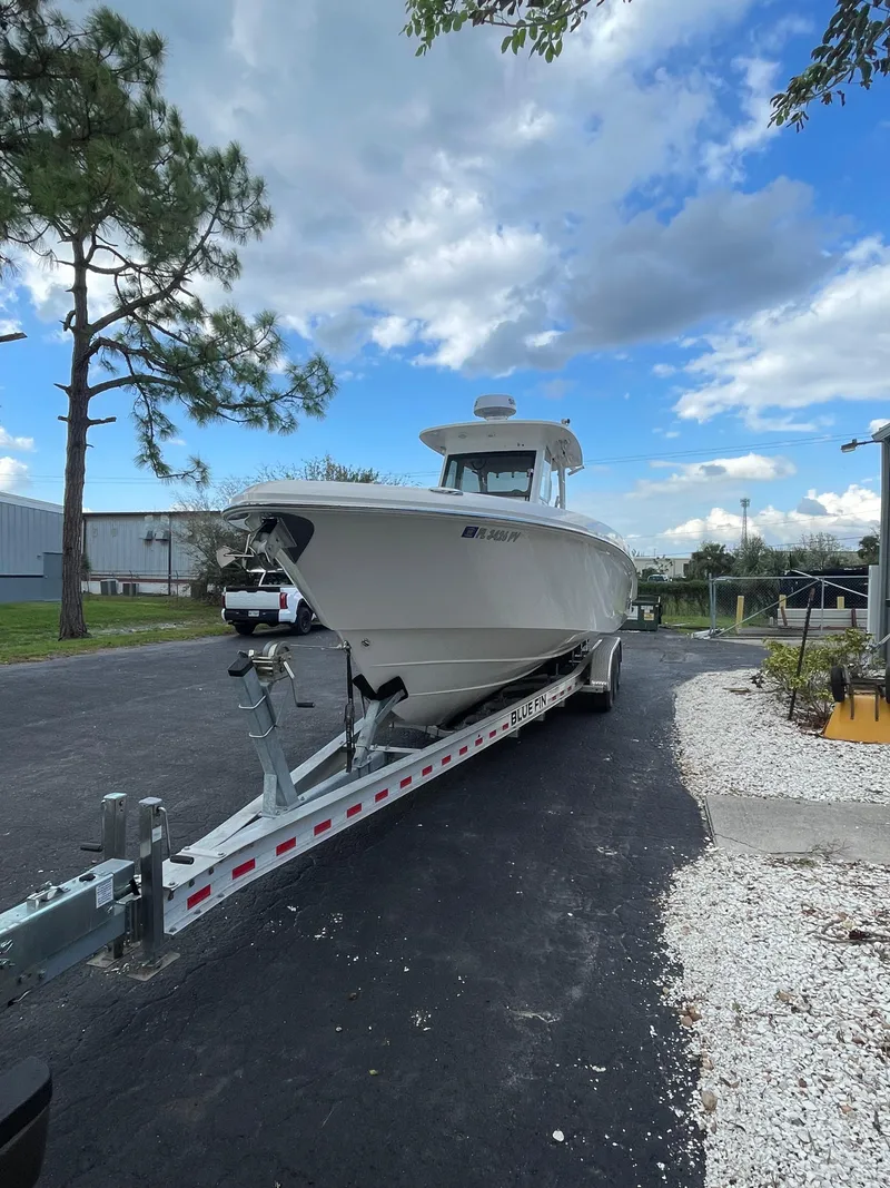 Slide: The Image of 2014 Everglades 325 Center Console boat on trailer, parked outdoors under a partly cloudy sky. - 16