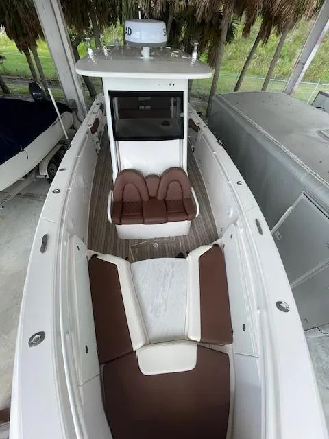 Slide: The Image of 2014 Everglades 325 Center Console boat with brown and white seating, docked under shelter. - 30