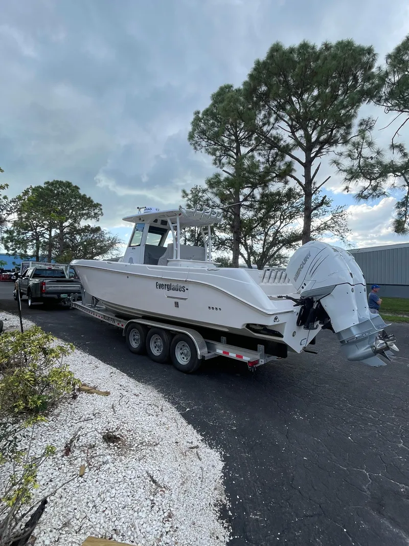 Slide: The Image of 2014 Everglades 325 Center Console boat on trailer, parked outdoors near trees. - 5