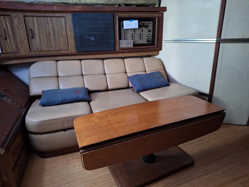 Slide: The Image of 1985 Sea Ray 390 Express Cruiser interior with beige sofa and wooden table. - 11