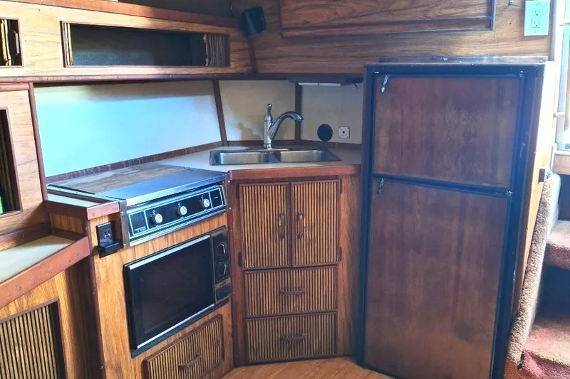 Slide: The Image of 1985 Sea Ray 390 Express Cruiser kitchen with wood cabinetry, sink, stove, and refrigerator. - 14