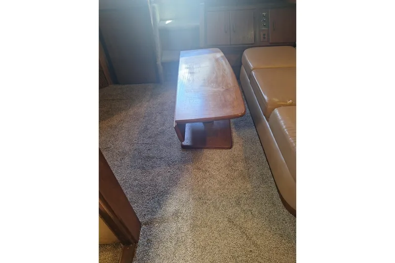 Slide: The Image of Interior of 1985 Sea Ray 390 Express Cruiser with wooden table and beige seating. - 21